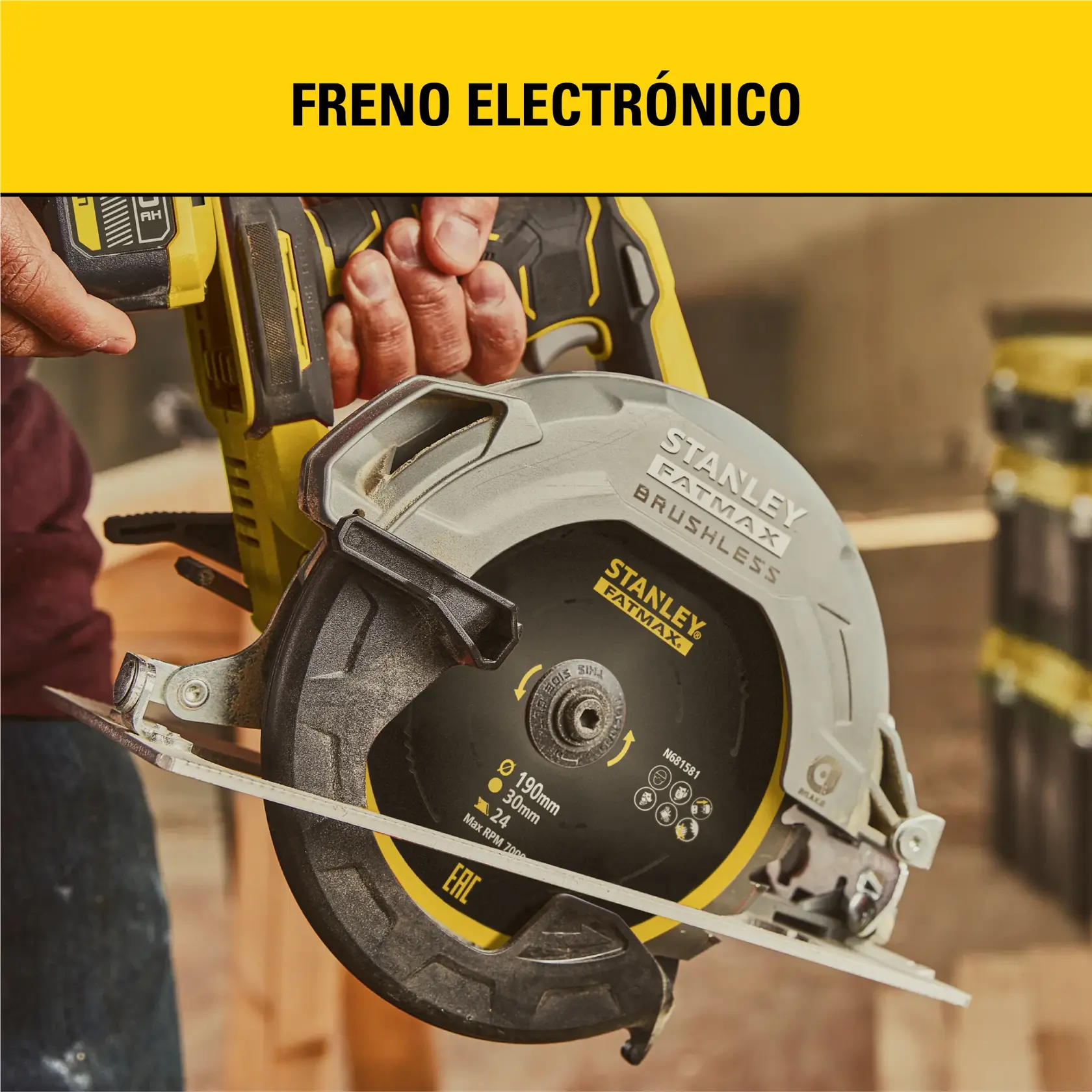Primer plano de una persona sosteniendo una sierra circular STANLEY FATMAX BRUSHLESS con hoja de 190 mm, mostrada en un taller. En la parte superior de la imagen aparece el texto 'FRENO ELECTRÓNICO'.