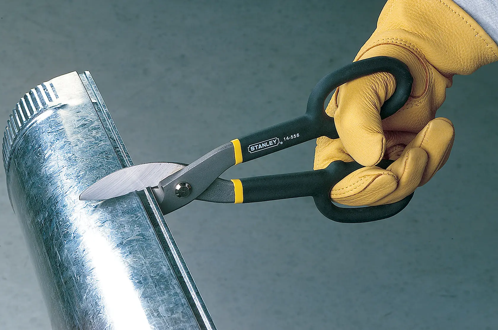 Stanley 14-556 tesoura para cortar metal em uso, cabos preto e amarelo, cortando tubo galvanizado.