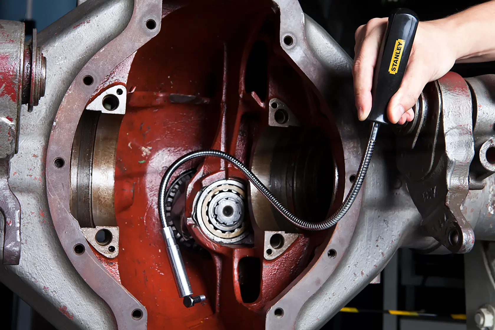 Foto da ferramenta magnética flexível STANLEY 78-020 sendo usada para pegar peças pequenas em máquina.