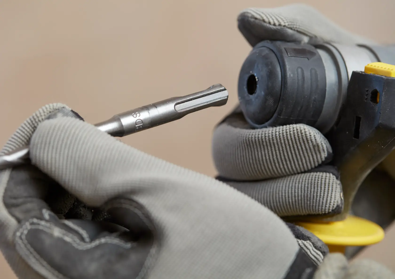 Stanley SBH900M2K-B3 broca insertándose en herramienta eléctrica, fotografía en primer plano de manos con guantes.