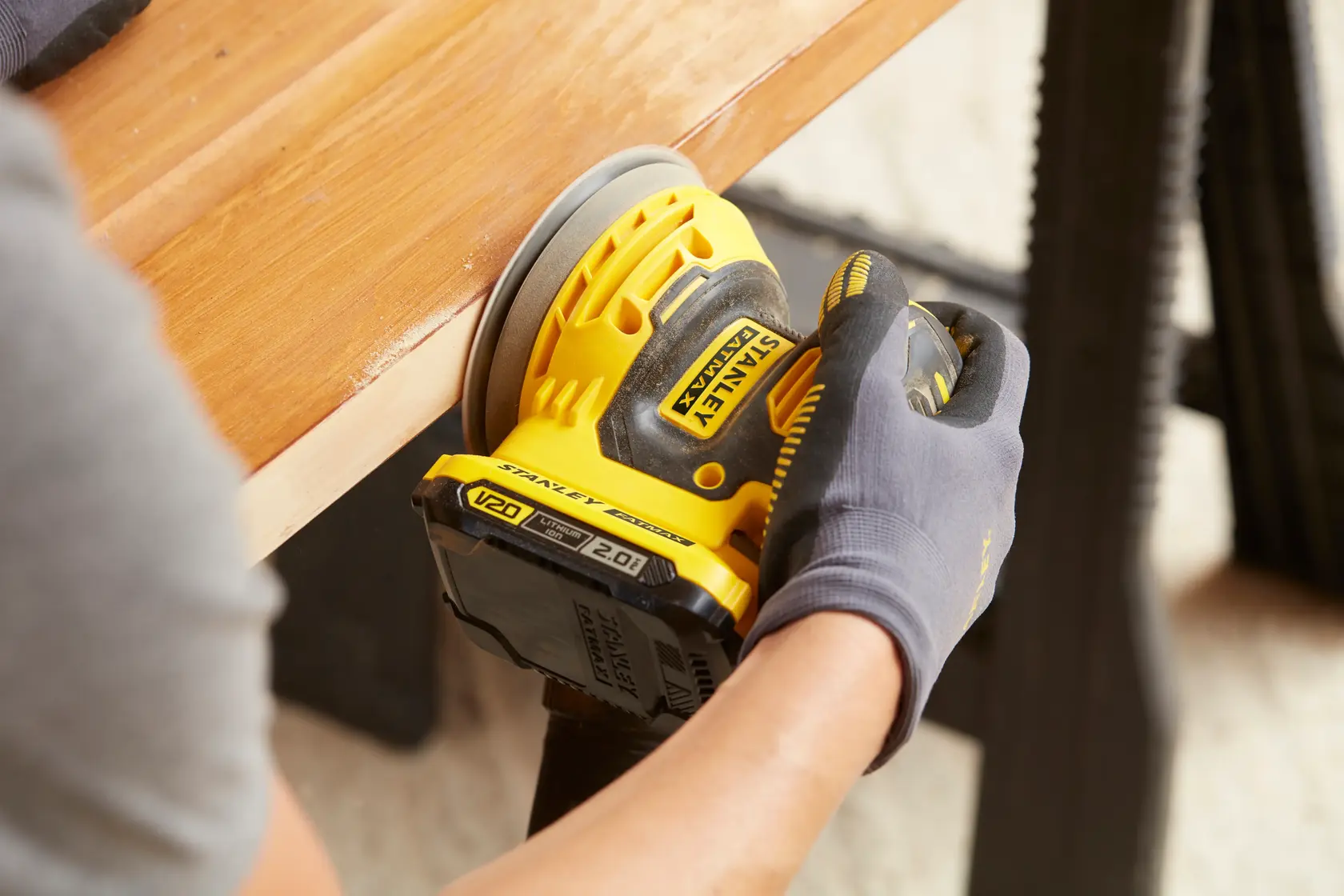 Foto de lijadora orbital STANLEY SCS220B, SCS220B-B3, SCS220-B2, SCS220 lijando madera con guante.