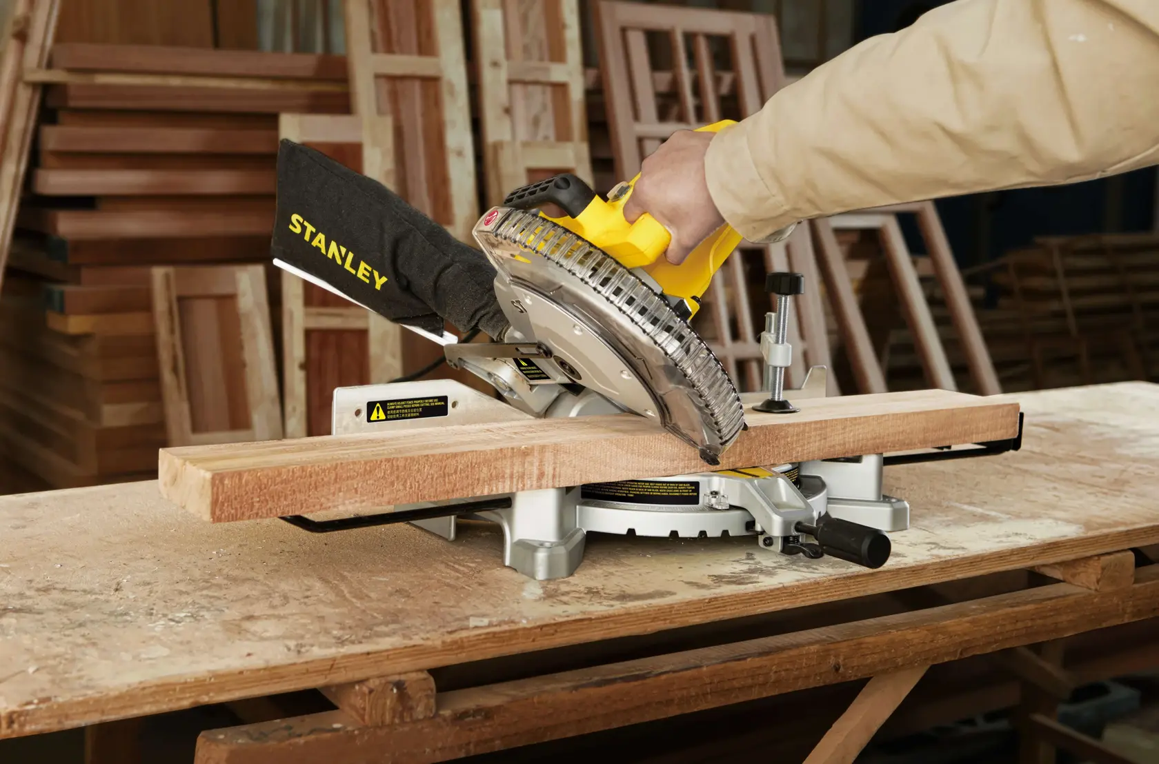 Sierra de inglete STANLEY SM16-B3 cortando madera en taller, ángulo lateral cercano.