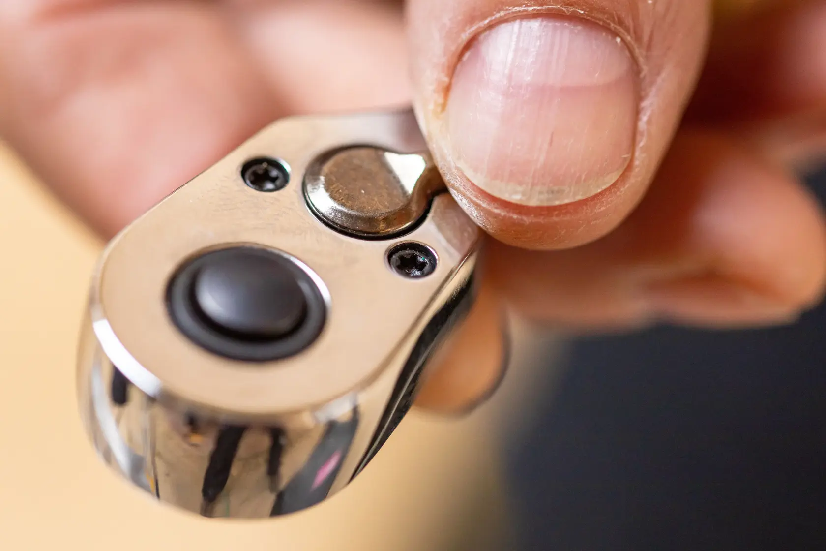 Close-up da catraca STANLEY STMT82828-LA com polegar no interruptor, fotografia de detalhe do produto.