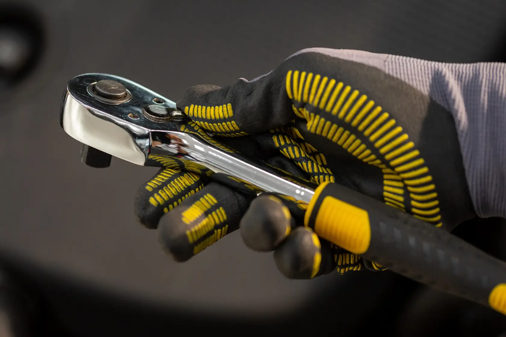 STANLEY STMT82830-LA catraca segurada por mão com luva, close-up com detalhe de cabo preto e amarelo.